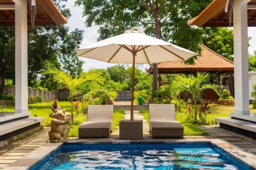 una piscina con 2 sillas, una sombrilla y un animal en UCU VILLAGE at ULUWATU JIMBARAN, en Jimbaran