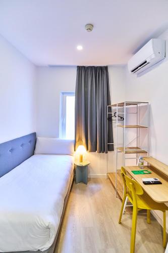 a room with a bed and a table and a desk at Hotel Gran Vía by gaiarooms in Salamanca