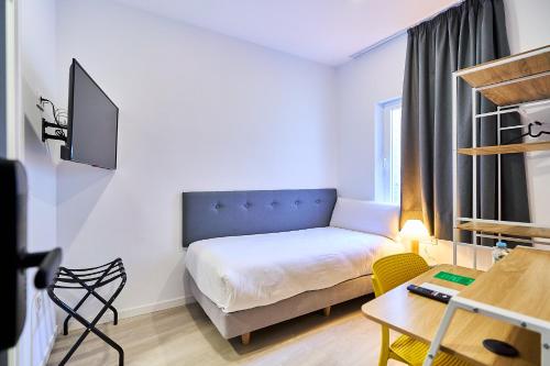 a small room with a bed and a desk at Hotel Gran Vía by gaiarooms in Salamanca