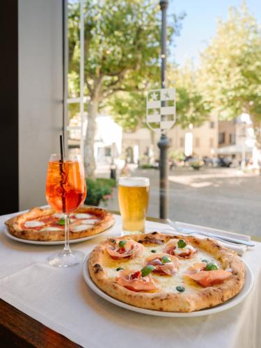 two pizzas on a table with a glass of beer at Hotel Royal Victoria, by R Collection Hotels in Varenna