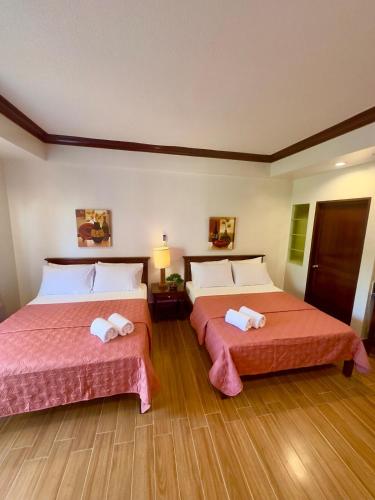 two beds in a hotel room with two bedsvisor at Club Balai Isabel Taal Lakeview 305 Malvar in Talisay