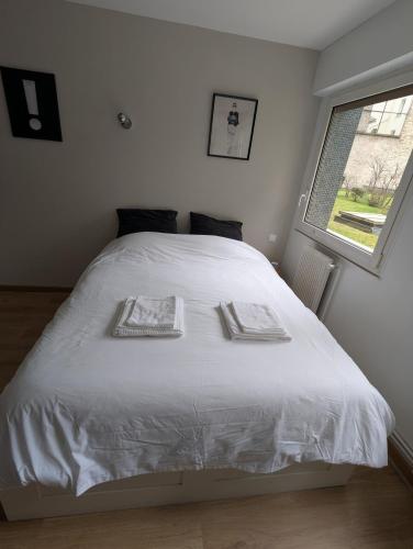 une chambre avec un lit blanc avec deux serviettes dessus dans l'établissement Studio équipé proche Tour Eiffel, à Paris