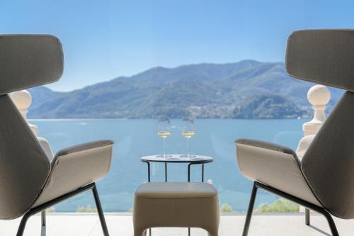 two glasses of wine on a table in front of a lake at Hotel Royal Victoria, by R Collection Hotels in Varenna
