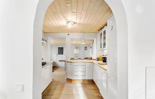 a kitchen with white cabinets and a wooden ceiling at Nice Home In Nexø With Wifi in Neksø