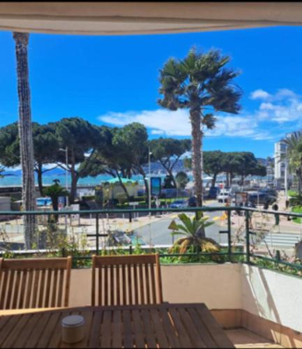 - un balcon avec 2 bancs en bois et des palmiers dans l'établissement Face à la mer et à 2 pas des plages Juan les Pins 'Tout à pied', à Antibes