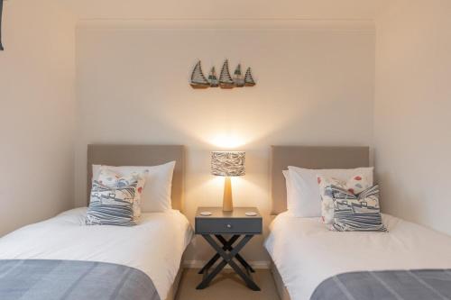 two beds in a room with a lamp on a table at Silver Shore in Southwold