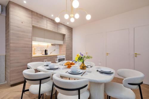 une salle à manger avec une table et des chaises blanches dans l'établissement Sophie Stay Montorgeuil -2BR 6P Wi-Fi, à Paris