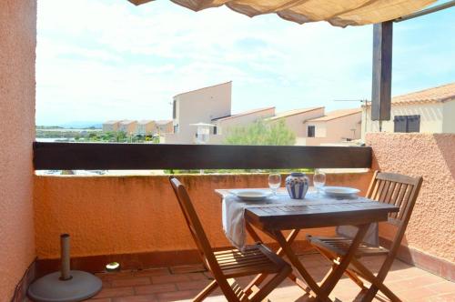 une table et des chaises sur un balcon avec un parasol dans l'établissement Appart 2 pièces 4 couchages PORT LEUCATE NATURISME PL010-902, à Port-Leucate