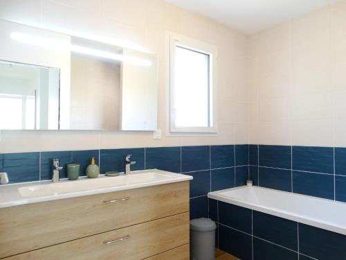 a bathroom with a sink and a tub and a mirror at Maison 6 avec piscine chauffée à St-Hilaire in Saint-Hilaire-de-Riez