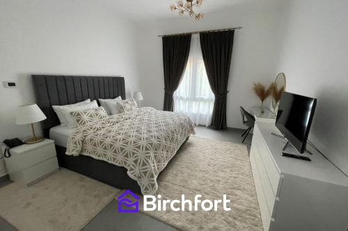 a bedroom with a bed and a flat screen tv at Birchfort - Newly renovated unique 1 bedroom apartment in Dubai