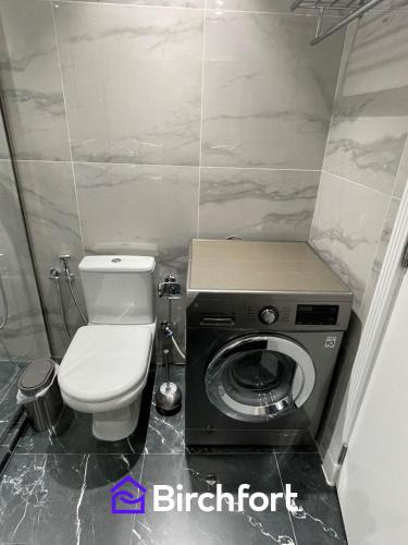 a bathroom with a toilet and a washing machine at Birchfort - Newly renovated unique 1 bedroom apartment in Dubai