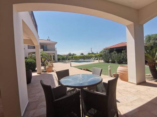 a patio with a table and chairs and a pool at Orchard Blossom Private Villa With Pool in Phrenaros