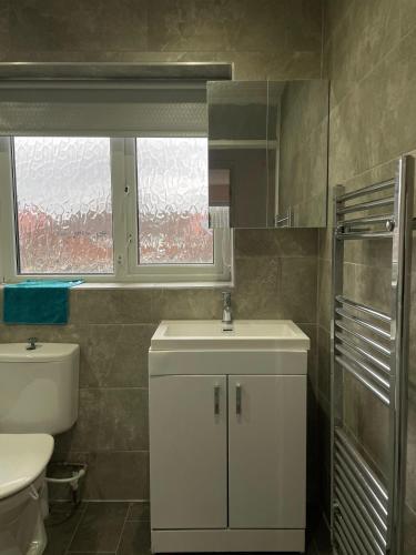 a bathroom with a sink and a toilet and a window at serenity suite musden walk in Manchester