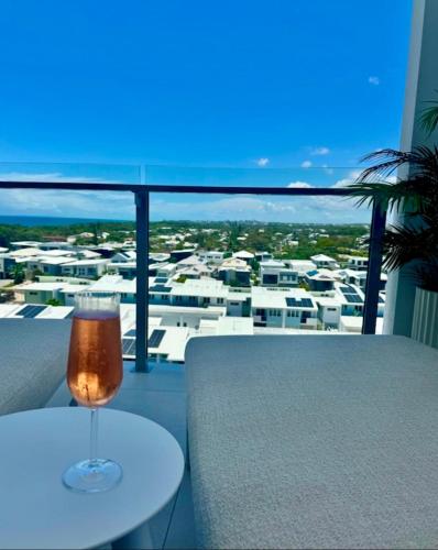a glass of wine sitting on a table on a balcony at Azzure Bokarina Penthouse- Brand New- Ocean View- Resort Style Pool- Steam Room in Bokarina