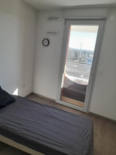 - une chambre avec un lit et une fenêtre avec une horloge dans l'établissement L'étoile, à Toulouse