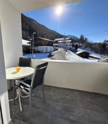 a balcony with a table and chairs and a snow covered mountain at Apartment Oberleins I in Arzl im Pitztal