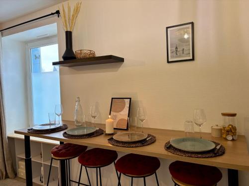a table with four stools with wine glasses on it at Limone Guest - Appartement Cosy - 5 min des plages in Larmor-Plage
