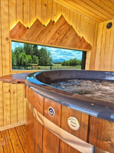 a tub in a wooden house with a window at Natur House Beskidy - dom z drzewa księżycowego z SAUNĄ i BALIĄ Jacuzzi!! in Ślemień