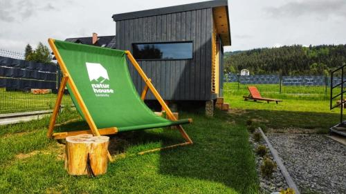 a green lawn chair sitting next to a tiny house at Natur House Beskidy - dom z drzewa księżycowego z SAUNĄ i BALIĄ Jacuzzi!! in Ślemień