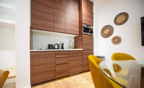 une cuisine avec des placards en bois et une table avec des chaises jaunes dans l'établissement CIA - Notre Dame spacious Home, à Paris