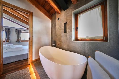 a bathroom with a large tub and a bedroom at Les Chalets de Rose in Breuil-Cervinia