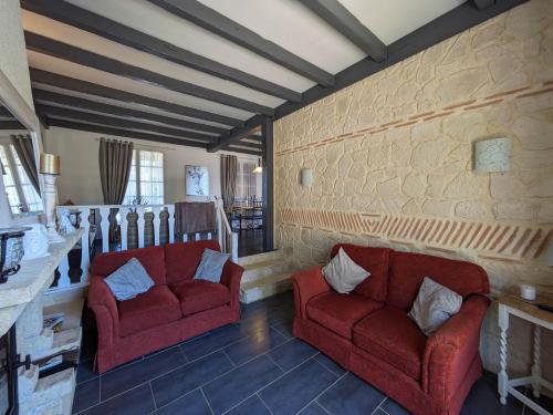 - un salon avec deux chaises rouges et un mur en pierre dans l'établissement Gite Le Petit Wren - avec piscine et vue, à Fumel