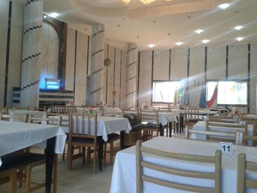 Fanara Apartments Armed Forces في فايد: مطعم بطاولات وكراسي مع طاولة قماش بيضاء