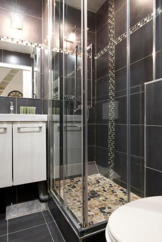 une douche avec une porte vitrée dans une salle de bain dans l'établissement CIA - Faubourg Montmartre Studio, à Paris