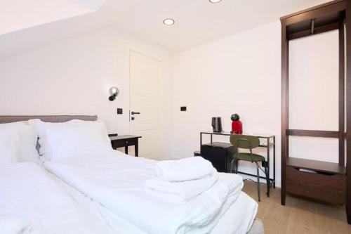 a bedroom with a large white bed and a desk at Tudisi Loft Room in Dubrovnik