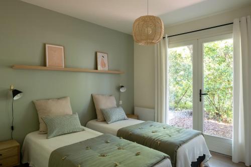 deux lits dans une chambre avec une fenêtre dans l'établissement Villa Horizon, proche plage, à La Teste-de-Buch