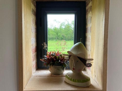 a doll sitting on a window sill next to a plant at Les 9 Hirondelles in Charrin