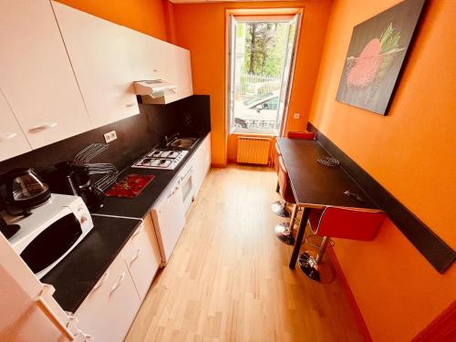 - une cuisine avec des murs orange et un comptoir dans l'établissement F3-Anémone, à La Bourboule