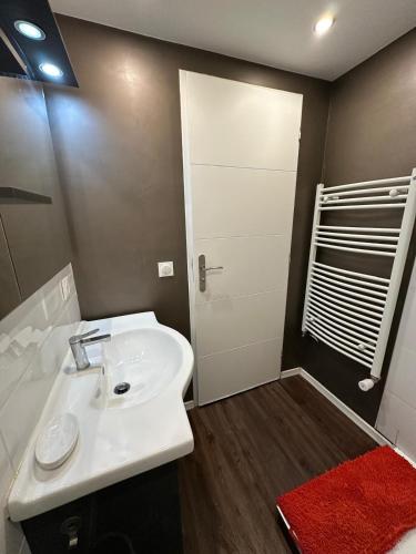 La salle de bains est pourvue d'un lavabo blanc et d'un tapis rouge. dans l'établissement Villa Eculaz, à Reignier-Ésery