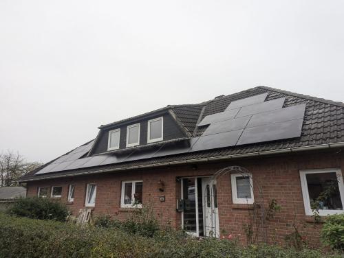 a house with a group of solar panels on the roof at Zimmer am Deich in Weyhe