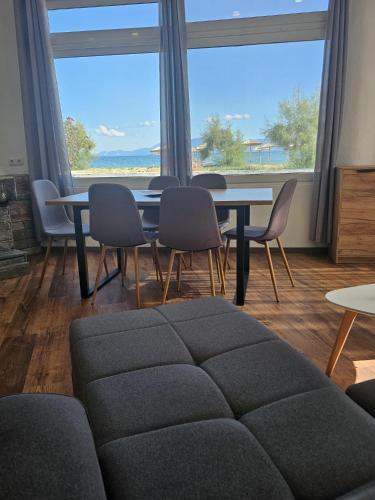 a living room with a table and chairs and a large window at Beach Apartment A in Néa Karváli