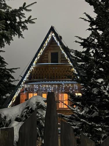 a log cabin with christmas lights on it at SkiBajkowa Chata in Szczyrk