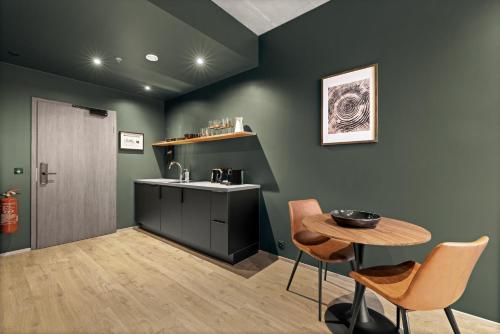 a kitchen with green walls and a table and a sink at Aurora Nooks by Heimaleiga in Reykjavík