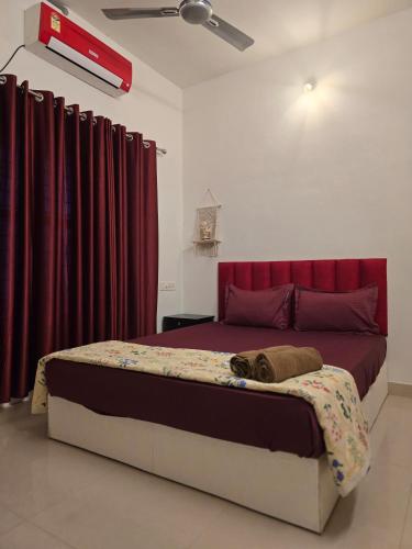 a bedroom with a large bed with red curtains at Lechalet in Varkala