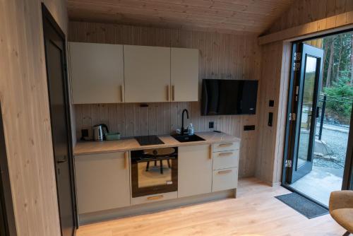 eine Küche mit weißen Schränken und einen TV in einem Zimmer in der Unterkunft Kulleseidkanalen gjestehamn in Bømlo