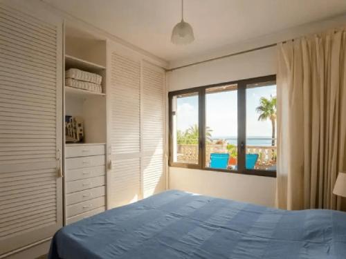 a bedroom with a blue bed and a large window at Atico la piramide en primera 1º línea de mar in Vinarós