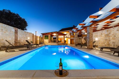 una piscina con una bottiglia di vino di Villa Mendula ZadarVillas a Pridraga