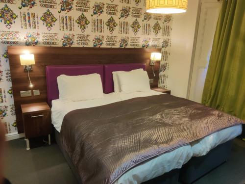 a bedroom with a large bed with a purple headboard at Chelsea House Hotel - B&B in London