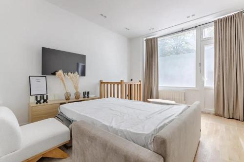 - une chambre blanche avec un grand lit et un canapé dans l'établissement Montparnasse - Modern & renovated 3BD for 8 guests, à Paris