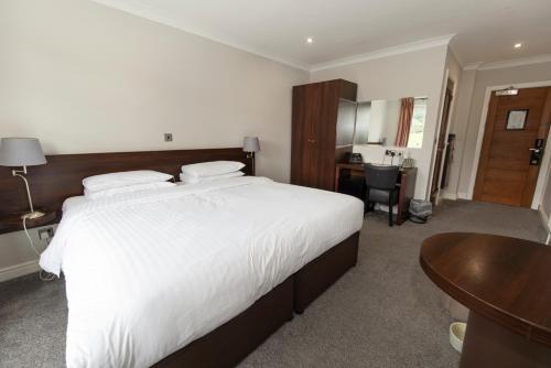 a bedroom with a large white bed and a desk at The Kinmel & Kinspa in Abergele