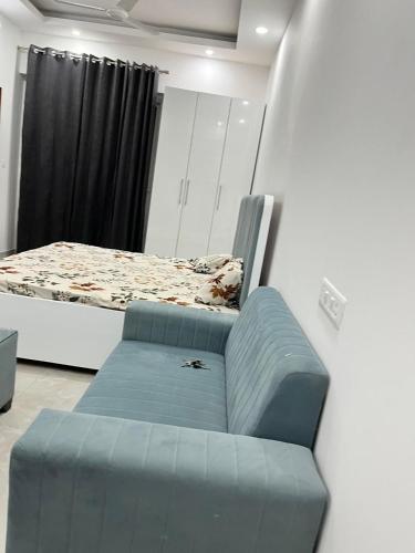 a bedroom with a bed and a blue couch at Golden palace studio in Noida