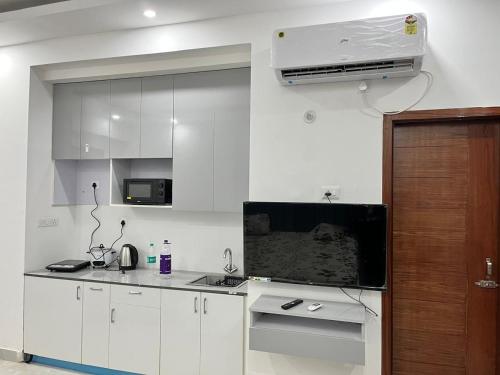 a kitchen with white cabinets and a air conditioner at Golden palace studio in Noida
