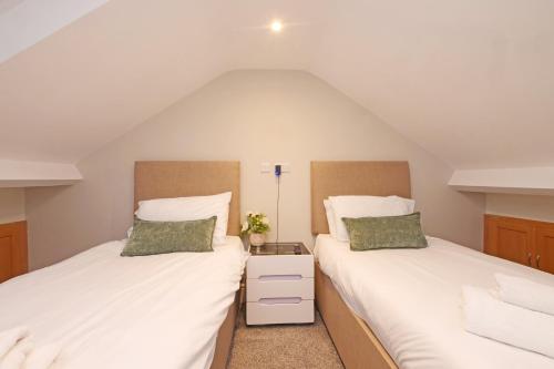 Dos camas en una habitación abuhardillada con sábanas blancas. en 59 Moss Green - Close to the city centre, en York