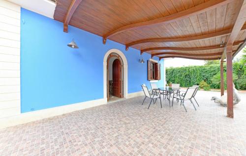 a patio with a table and chairs and a blue wall at Parisi in Floridia