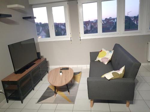 un salon avec un canapé, une table et une télévision dans l'établissement T2 tout confort, proche de la gare !, à Dijon