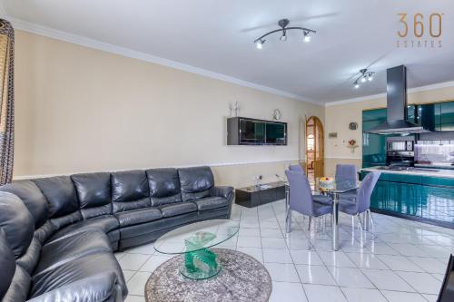 a living room with a leather couch and a table at Spacious 4BR Villa with Private pool, parking & BBQ by 360 Estates in Tal-Mirakli